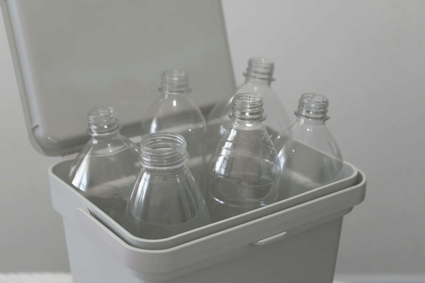 Empty plastic bottles sit in an open recycling bin.